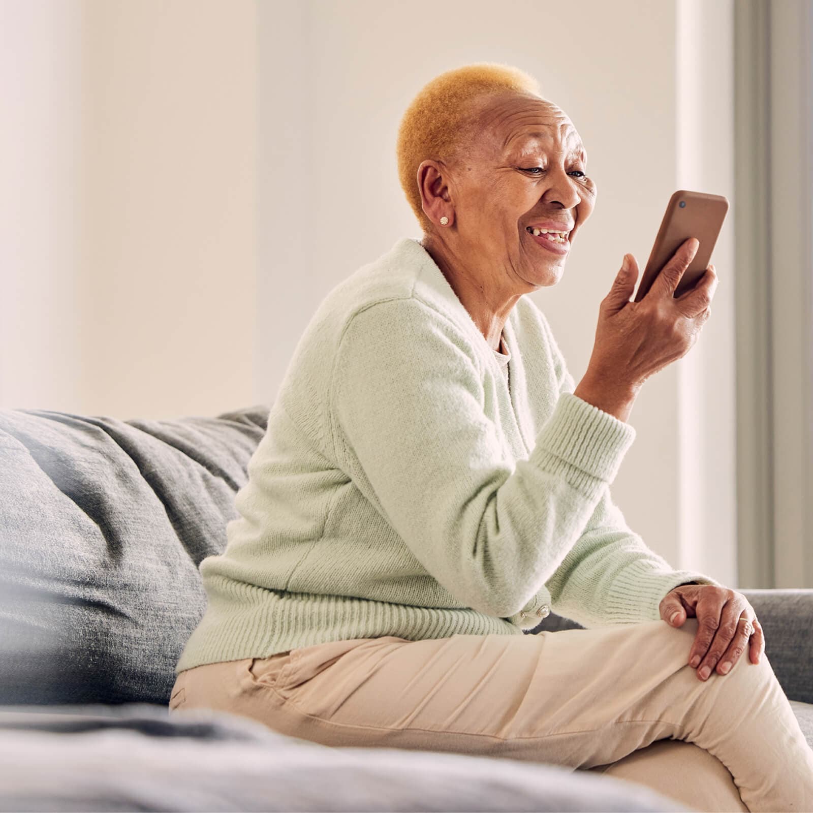 Elderly woman smiling while using a phone