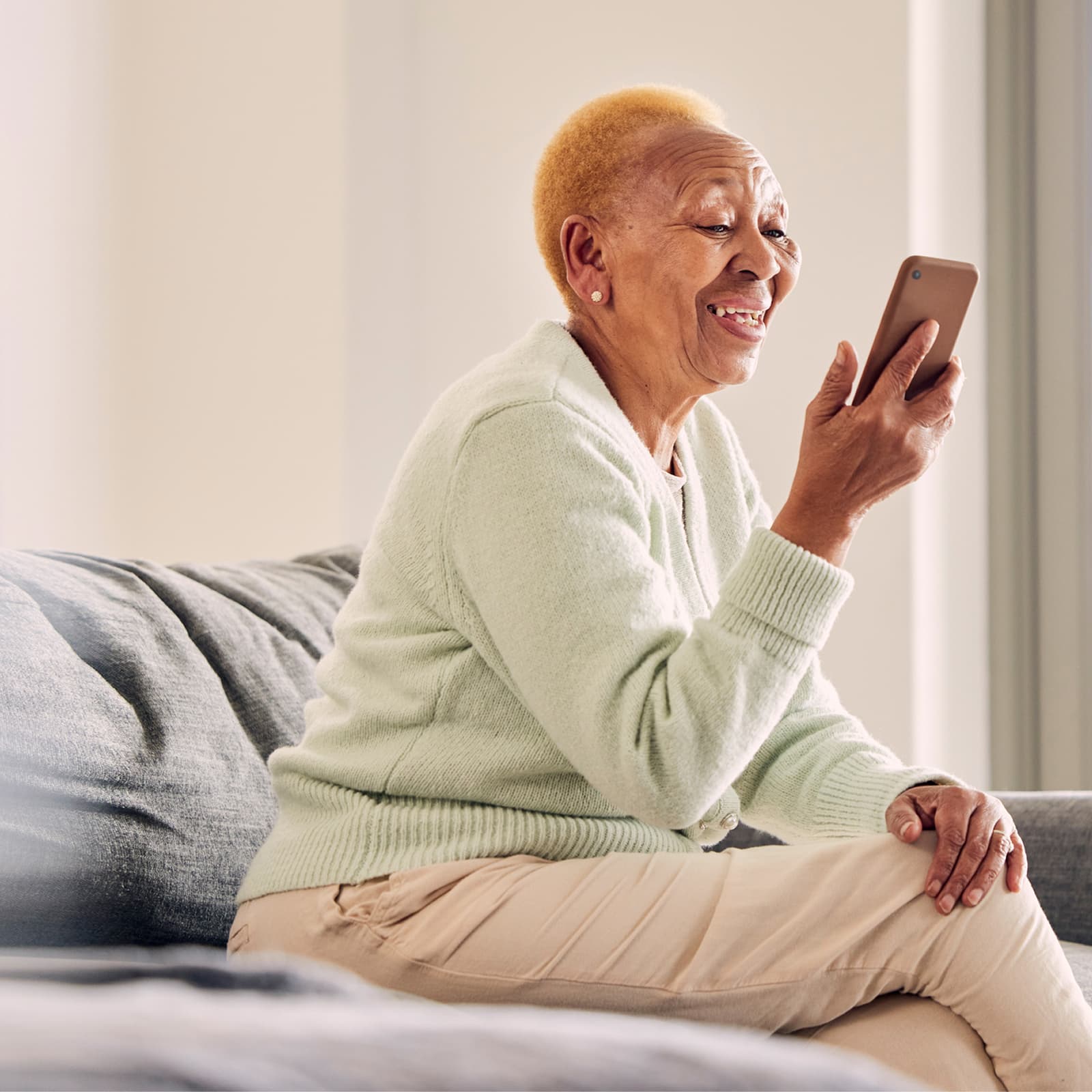 Elderly woman smiling while using a phone