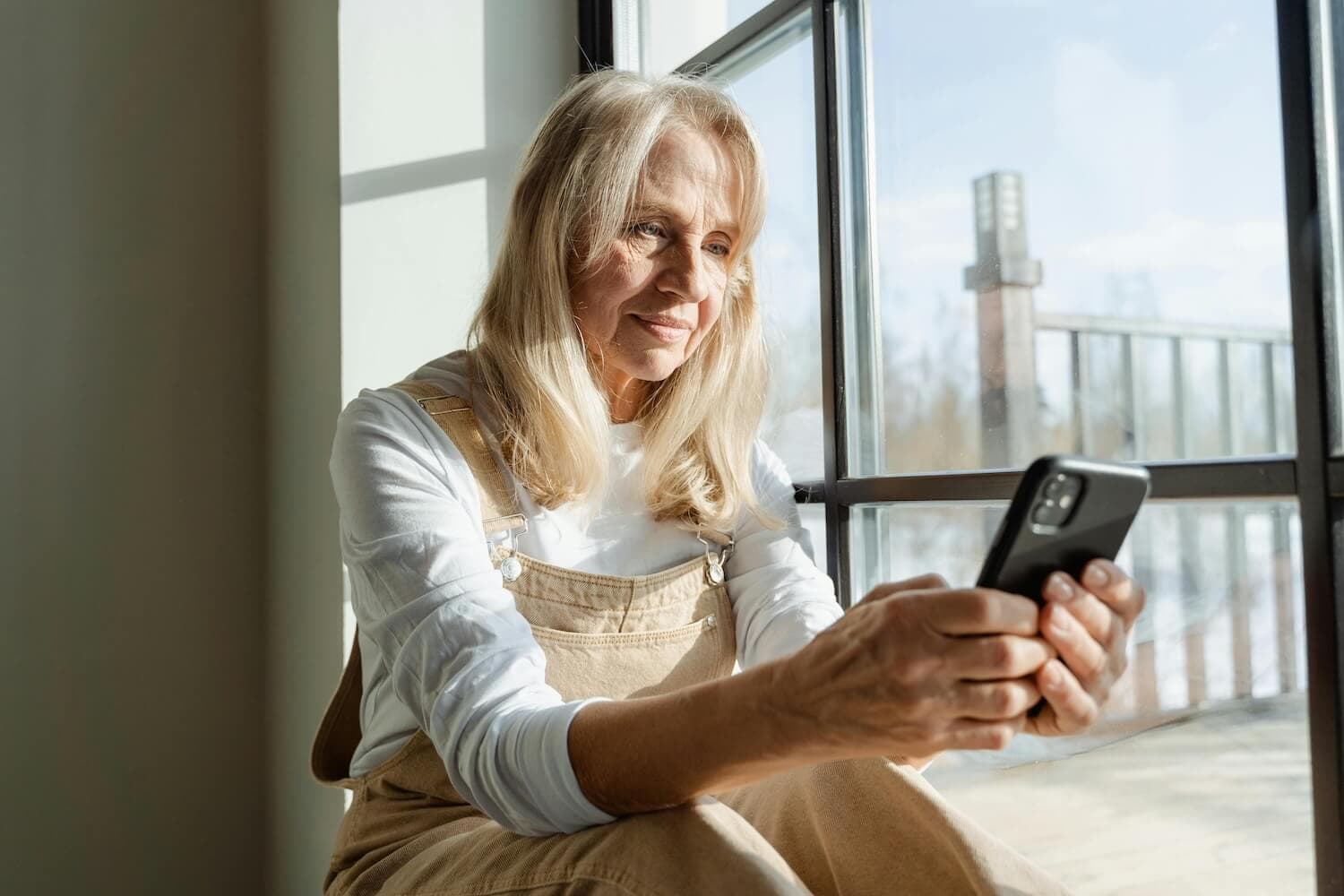 Woman sitting by a window looking at her smartphone